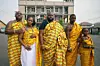 A family of five pose side by side wearing mustard-yellow kente cloth, a fabric native to Ghana.