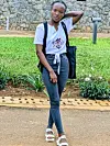 Chadia Uwineza poses for a photo in a white shirt and black denim pants.