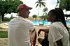 A man and woman in white shirts conversing as they look at each other by the poolside.