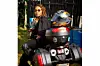 Udoh sits on a powerful touring motorcycle, looking directly into the camera. She\u2019s dressed in black riding gear with her helmet resting behind her, exuding elegance and strength.