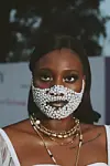 Nigerian woman wearing pearl mask and gold jewelry at Lagos Fashion Week 2019.