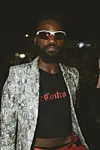 Nigerian man in snakeskin jacket, crop top and wraparound sunglasses at Lagos Fashion Week 2019.