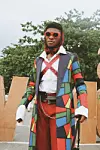 Nigerian man wearing colorful coat and red sunglasses.