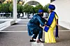 Two people in traditional wedding gear dance at their African wedding.