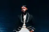 Nigerian Afrobeats singer Davido poses for a press image wearing baggy white jeans and a blue, dotted blazer.