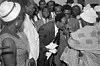 A photo of Kwame Nkrumah bending to have a drink from a cup held by another man.