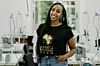 A photo of Mahlet Afework wearing a black t-shirt and blue denim pants, surrounded by sewing machines.