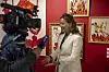 El Glaoui wearing a white blazer and speaking to an AFP reporter in front of a red wall adorned with several red and golden art pieces.
