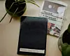 A worn black photo album labeled 'Family Maindron' sits on a windowsill next to a potted plant, alongside an old photograph wrapped in plastic with 'Original \u00e0 conserver!' written on it.