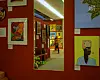 A person walks through a vibrant art gallery filled with colorful, abstract and figurative paintings, captured through a large mirror reflecting the opposite wall and creating a layered visual effect.