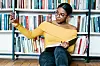 An image of a woman taking a selfie in front of a shelf of books