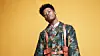 Nasty C poses in front of an amber backdrop.