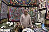 Hossam Mahmoud, co-owner of Al Farouk shop in front of colorful khayamiya artworks.