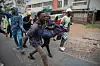 Young protesters demonstrating on a street in Mozambique, with one man shouting while others move energetically