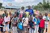 Ahmed Mire, wearing a hat, stands with a group of smiling children after a skateboarding session in Nairobi. The children hold skateboards and new shoes.