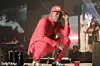 An image of Olamide dressed in red, crouching on a stage, holding a microphone in his hand