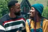 A man and woman, in a scene from the Kenyan film Sayari, sit close together outdoors, looking into each other’s eyes; the man wears a striped sweater, and the woman wears a teal beanie, mustard top, and denim overalls, with a cozy cabin and greenery in the background.