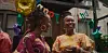 A still of the film, Nanny, showing two women, dressed in colorful attire smiling at a birthday party.