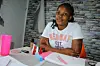 A young woman poses for a photo in a white t-shirt with some beauty products on a table in front of her in Francistown, Botswana, on January 11, 2024.