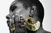 A model wears a brilliant gold earring and finger rings designed by Adele Dejak, an African jewelry designer.