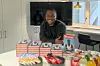 A photo of Chukwuebuka Ibeh resting on a table surrounded by multiple copies of his books, snacks, and drinks.