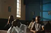 A still from Shimoni of a man sitting at a pew in a church.