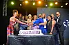 A group of people hold hands in celebration over a cake