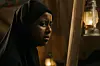 An image from the film of a woman wearing a hijab in a lamp-lit room.