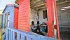 A man sits in an empty beach hut painted red in Cape Town, South Africa