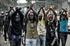 Protesters make signs with their arms in front of Kenya police officers during a demonstration against tax hikes as Members of the Parliament debate the Finance Bill 2024 in downtown Nairobi, on June 18, 2024.