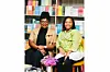 Two women smiling, seated in front of bookshelves filled with books, at Soma Nami Books.