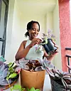 Wakisha Wazome repotting a striped plant on a balcony.