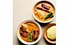Two bowls of West African groundnut soup with meat, okra, and vegetables served alongside white pounded yam or fufu.