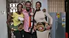 2 women flank a man, all holding boxing championship belts