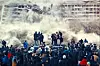 An image from the film of a building being demolished in front of a group of people.