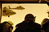 A camera view from behind a U.S. soldier sitting in a helicopter.