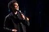 Trevor Noah in a black jacket with a microphone.