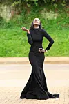 Ugandan sports journalist and analyst Usher Komugisha in a long black dress, face looking to the sky.