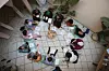 A shot from above, showing 12 women sitting on cushions in a circle, holding papers and listening to one woman share what she has written.