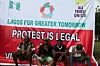 A photo of four male protesters sitting in front of a banner that says “protest is legal.”