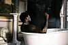 Nigerian artist Asake sits in a bathtub in a promotional image for his single “Badman Gangsta.”