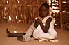 A five-year-old girl with a bandaged leg poses for the camera, her face serious.