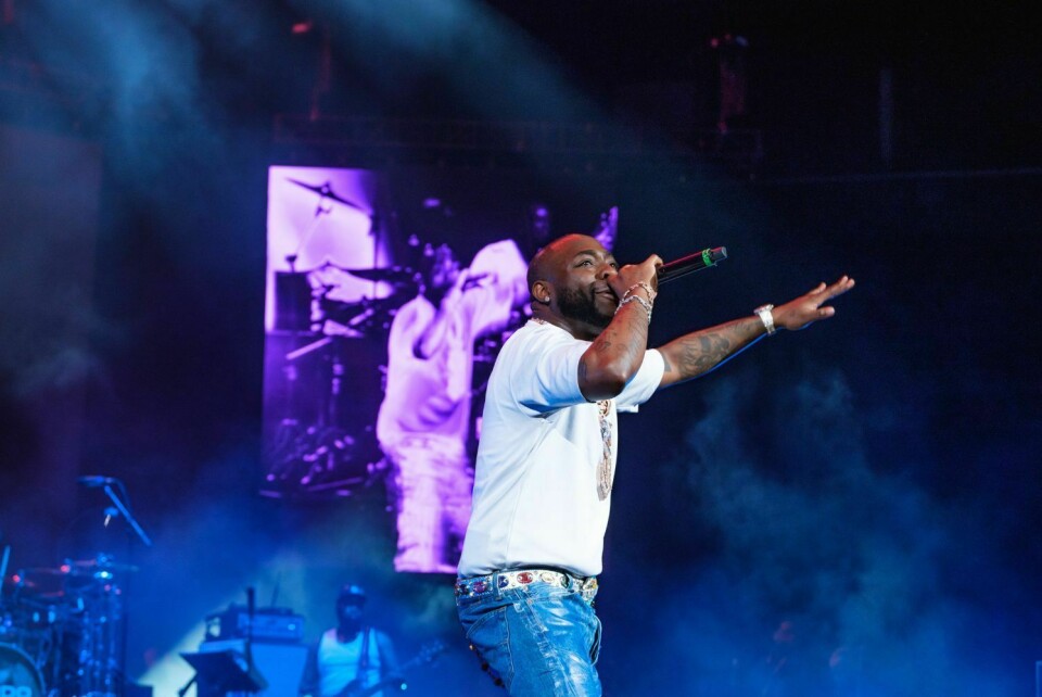 Davido performs live at the Barclays Center in Brooklyn, New York on July 31, 2025. Davido performs on stage, wearing blue jeans and a white shirt, mic in hand, band in the background