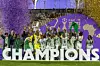 Nigeria's players celebrate, screaming, hands in the air, with the trophy on a podium in front of a big white CHAMPIONS sign