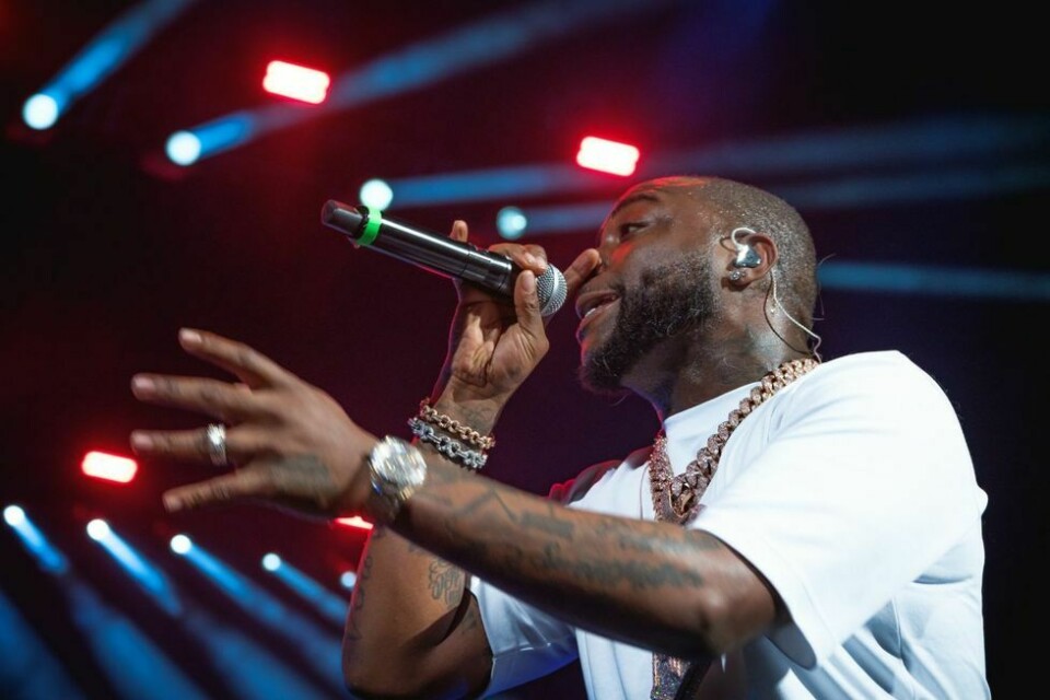 Davido live on stage wearing a white t-shirt, and a chunky silver chain