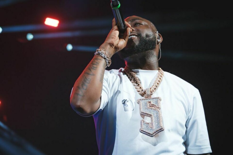 Davido live on stage wearing a white t-shirt, and a chunky silver chain